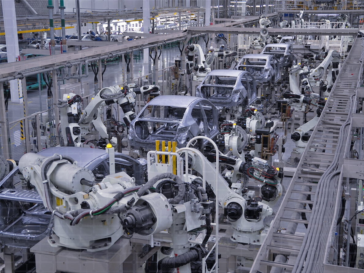 大型の自動ロボットが車の製造工場で稼働する様子